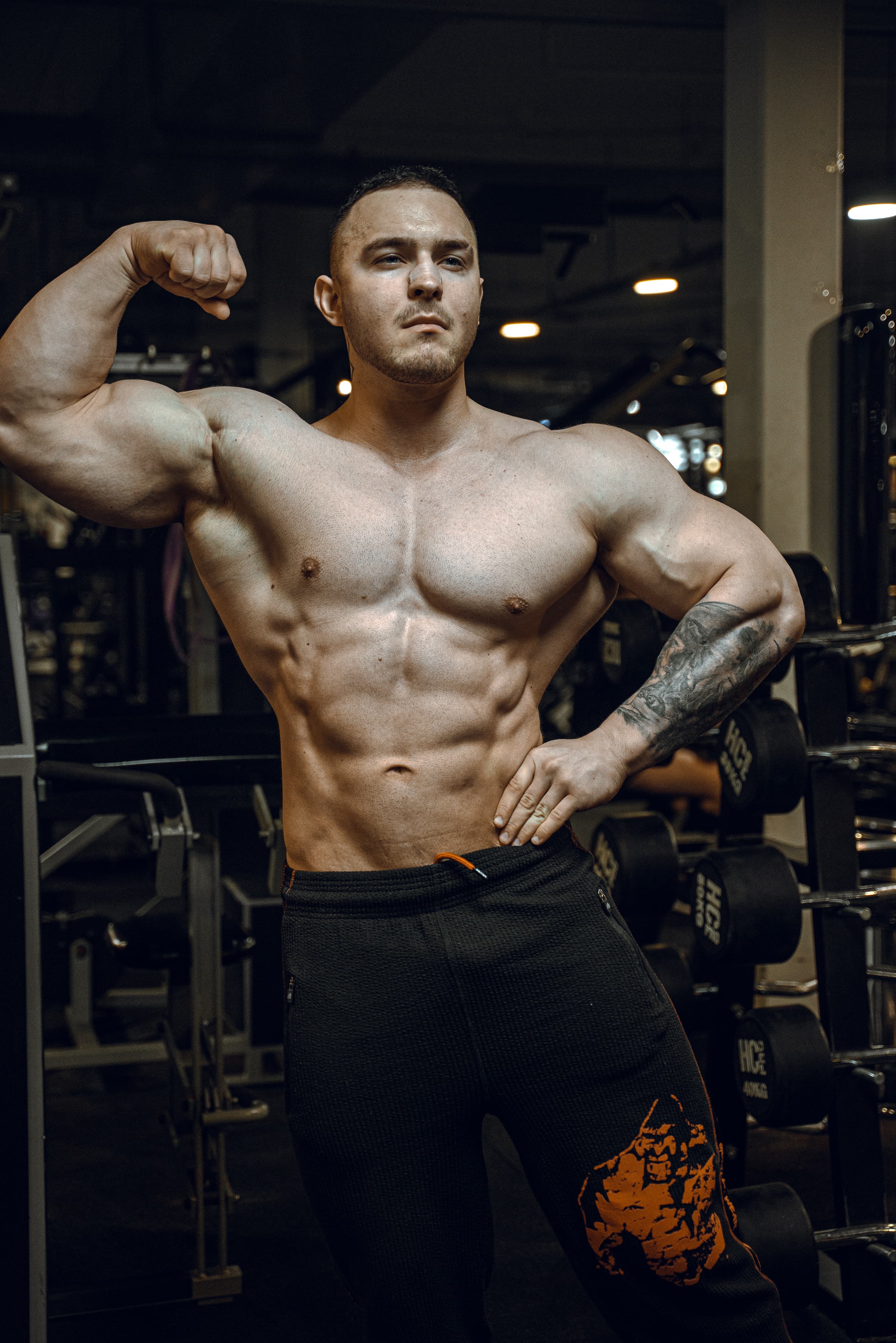 Muscular man flexing his arm in a gym setting